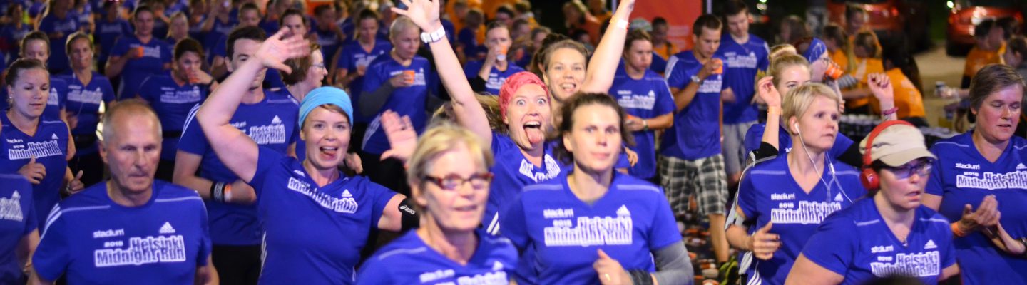 Löpare springer förbi vätskestationen och är peppade under Midnight Run Helsinki 2015