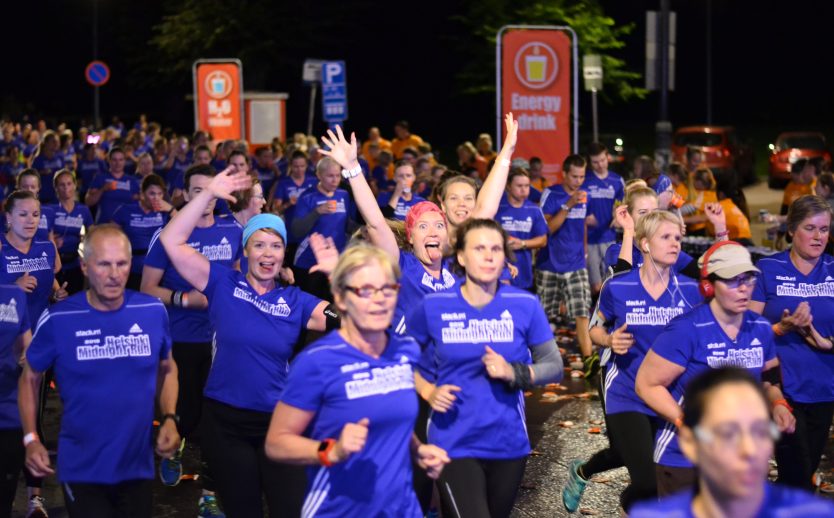 Löpare springer förbi vätskestationen och är peppade under Midnight Run Helsinki 2015