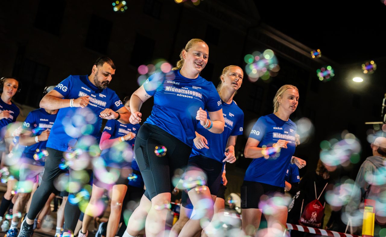 Leende löpare som springer genom blåsbubblor under Midnattsloppet Göteborg 2026