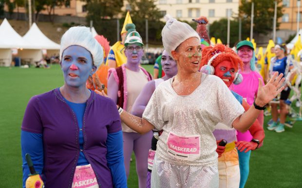 Maskeraddeltagare utklädda till troll väntar på catwalk under Midnattsloppet Stockholm 2026