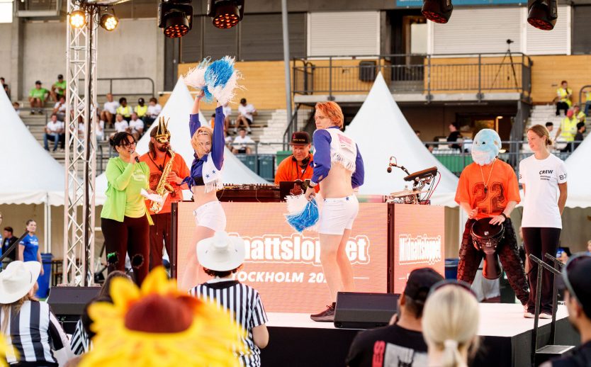 Maskeraddeltagare utklädda till cheerleaders går catwalk på scenen under Midnattsloppet Stockholm 2026