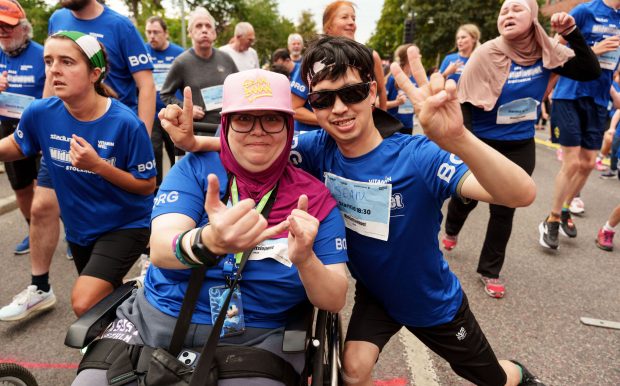 Två glada deltagare under Glada Midnattsloppet 2026 som gör handgester och taggar upp inför uppvärmning och start