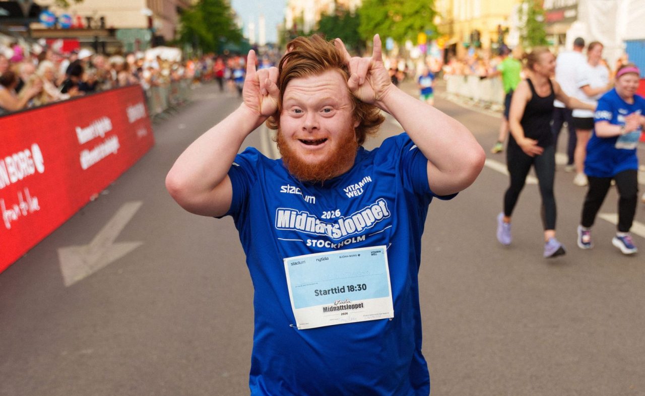 Löpare som gör rock and roll gest på väg in i mål under Glada Midnattsloppet 2026