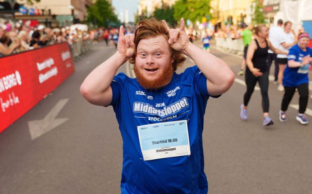 Löpare som gör rock and roll gest på väg in i mål under Glada Midnattsloppet 2026